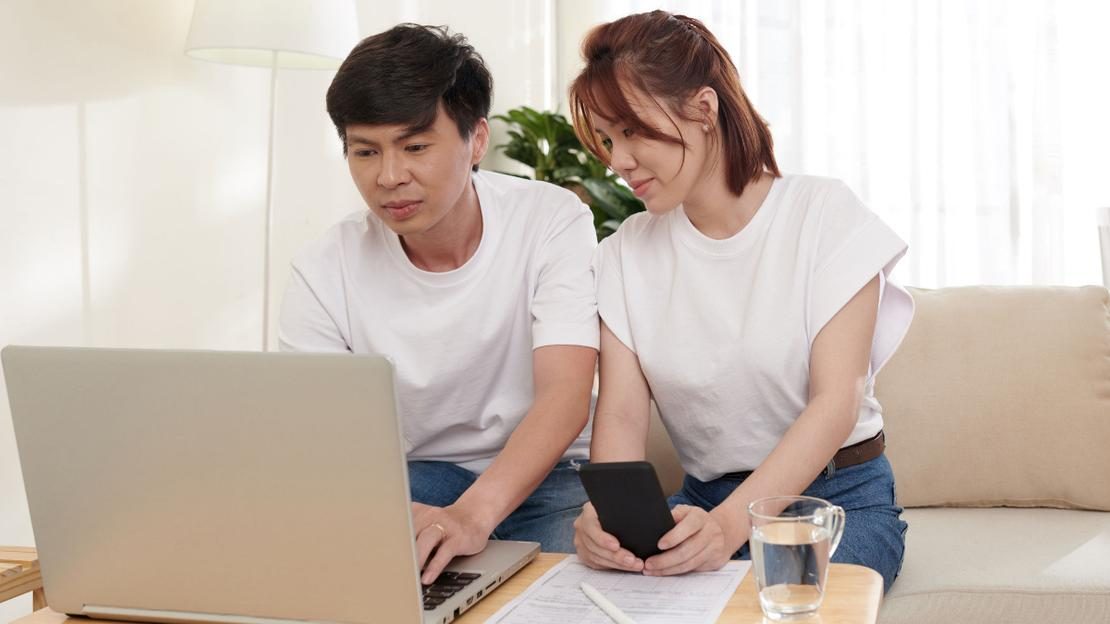 Singapore couple reviewing property financial planning documents — HDB upgraders comparing new launch versus resale condo options, budgeting for ABSD, downpayment and mortgage in 2026